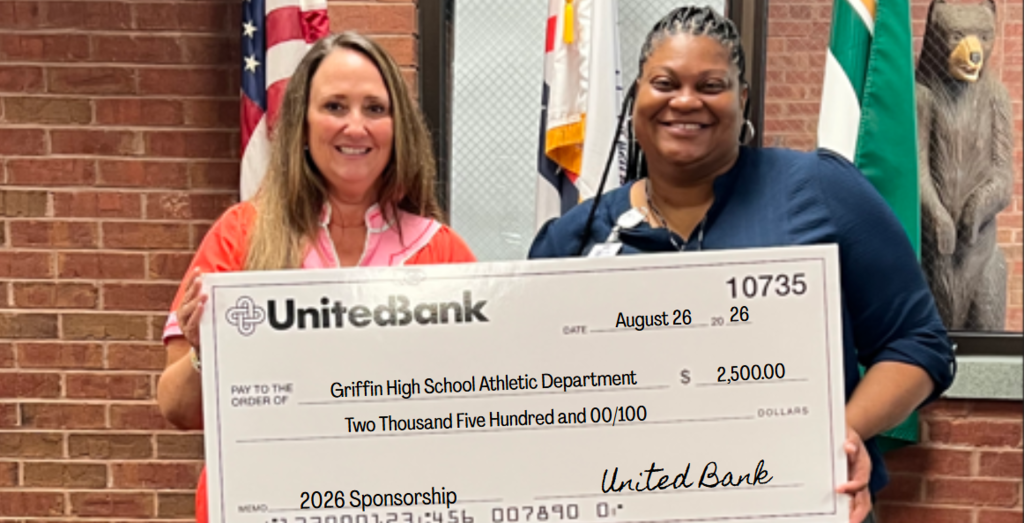 A United Bank representative presents Coach Jennifer Hill with a check for 2,500 dollars.