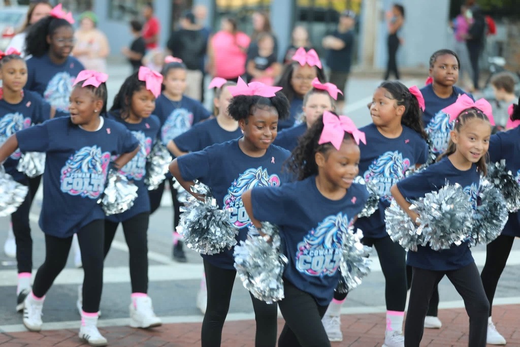 Cowan Colt cheerleaders marching and dancing down the parade route with silver pom-poms.