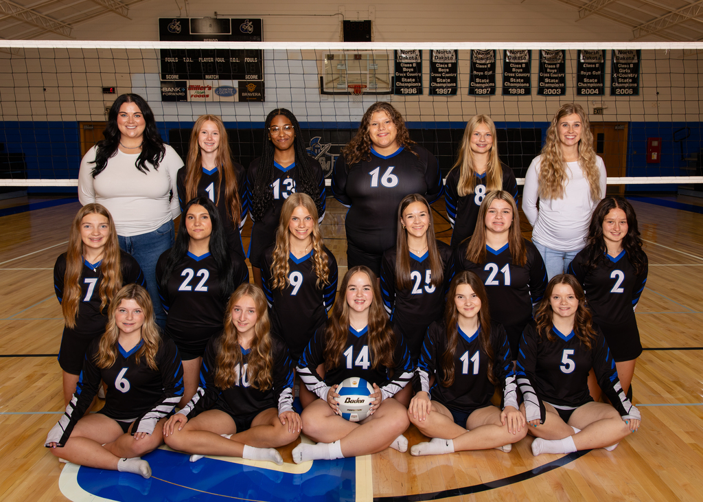 The first picture is a team photo of the Griggs-Midkota Titans C volleyball team. The players are wearing black uniforms with royal blue and white accents and are posed in three rows on a gym floor in front of a volleyball net. Two coaches stand in the back row. A player seated in the center of the front row is holding a blue-and-white volleyball. The gym background includes a basketball hoop, scoreboard, and championship banners. The second picture shows the schedule for the Carrington Cardinals “C” Jamboree on October 3, 2026. Ten teams are listed, including Griggs-Midkota as Team #7. Griggs-Midkota is scheduled to play Benson County (#8) at 9:15 AM on the South Court, Four Winds (#4) at 10:40 AM on the South Court, and Rugby (#9) at 1:20 PM on the North Court. The schedule also notes that teams should use Door 7 when arriving.