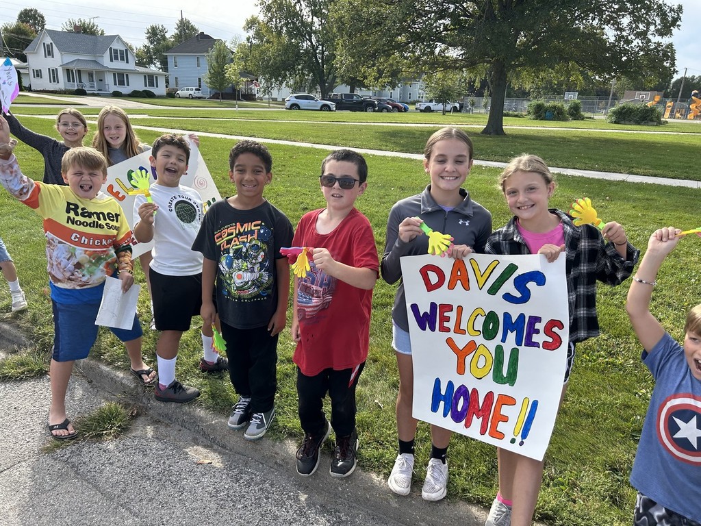 Students on curb with sign for parade