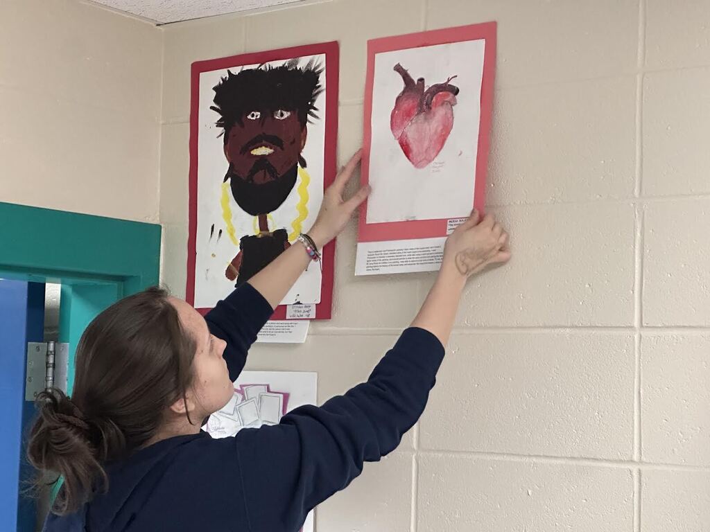 student hangs artworj