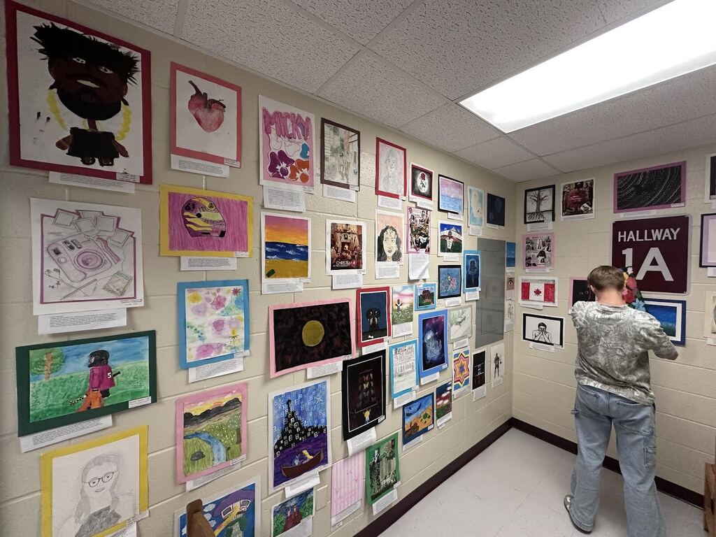 student in front of an artwork wall
