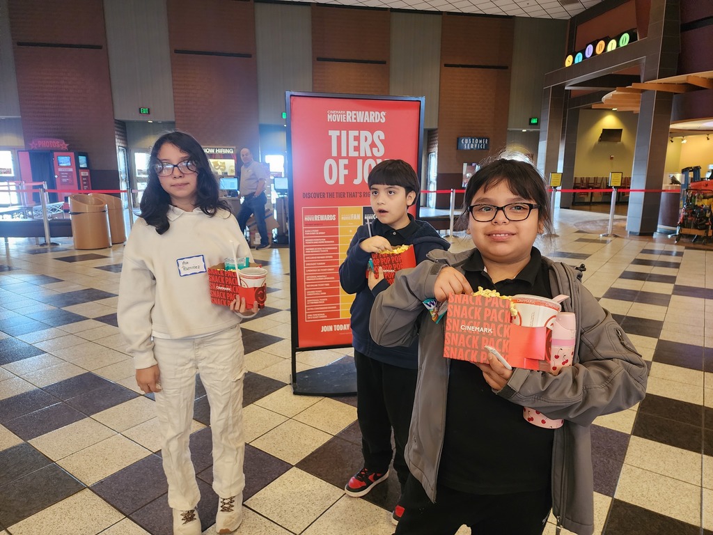 Boy and two girls with popcorn and drink combos, ready to enter the movie theater.