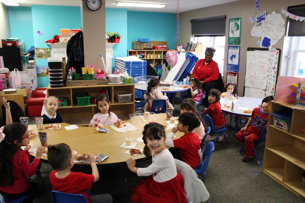 Pre-K children enjoying cupcakes at their Friendship Party in the classroom alongside their teacher
