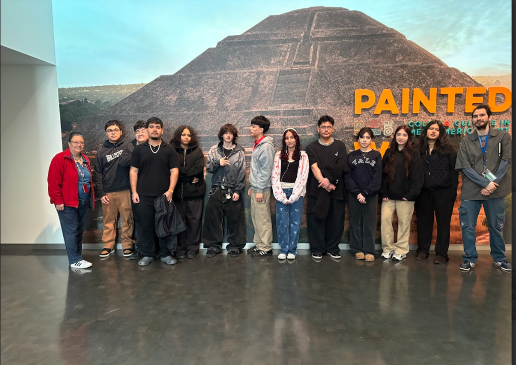 group of students and teachers posing in front of a mural