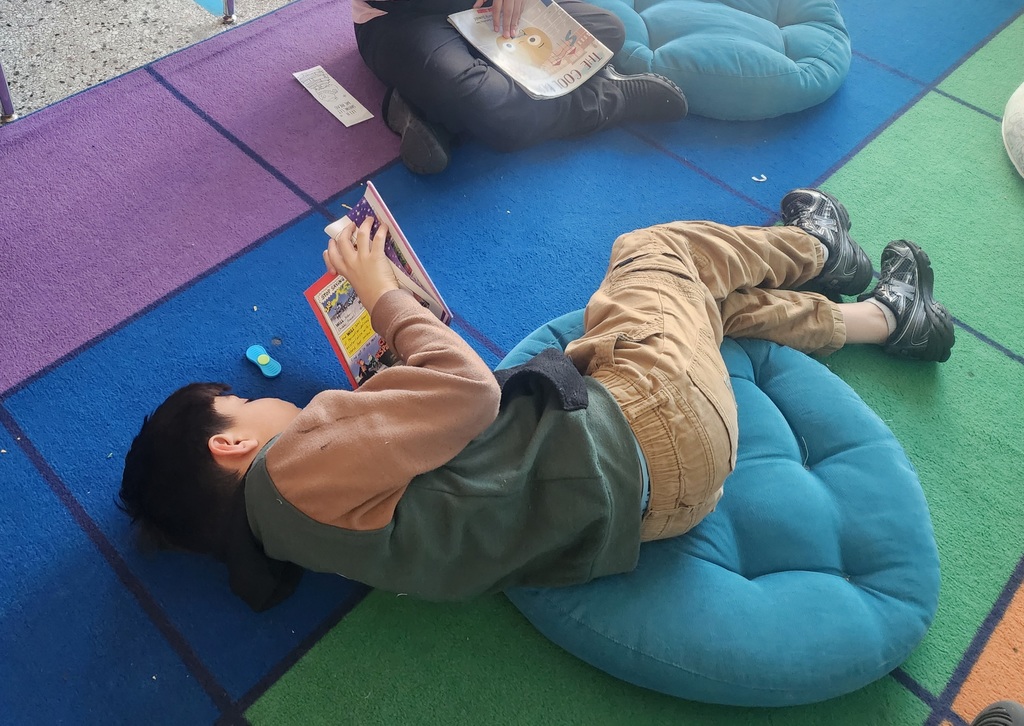 A student reading their favorite book on the floor, relaxed and happy.