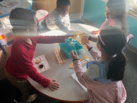 Kindergarten children making a toast with their classmates as part of a royalty-themed activity