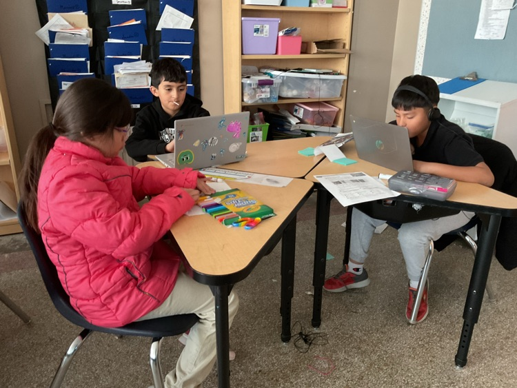 students sitting on their tables looking at a computer