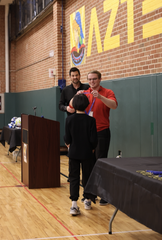 Mr. Shumsky putting a medal on a student
