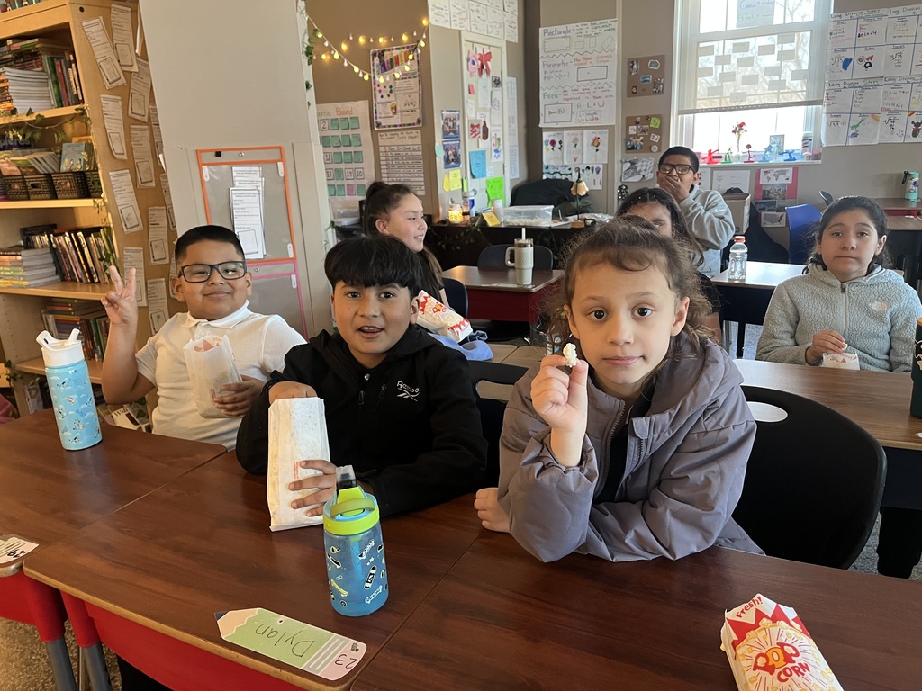 Children in their classroom eating popcorn — they were among the classes with the best attendance and received a popcorn party