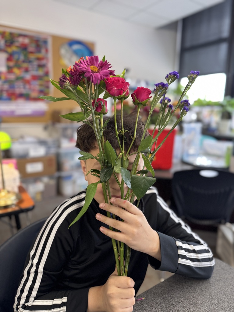 student holding his flower bouquet in front of his face