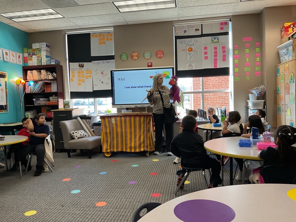 Children in the classroom attentive to a puppet presentation,An adult is holding a bird puppet
