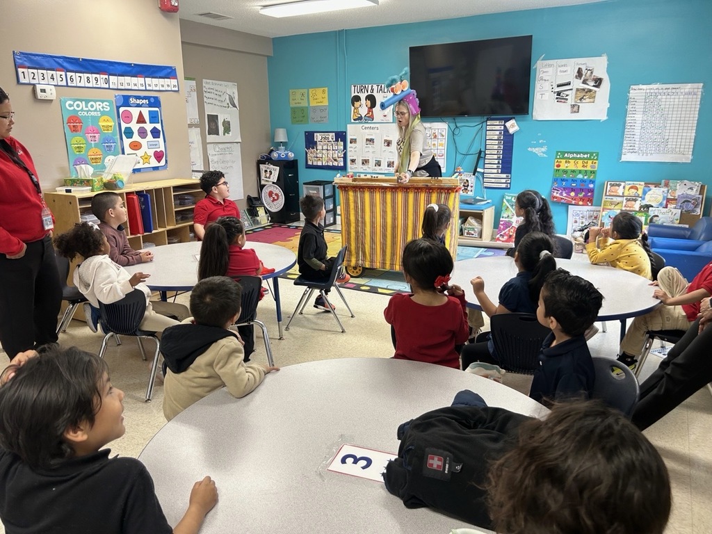 Students sitting in their classroom, attentive to a puppet presentation