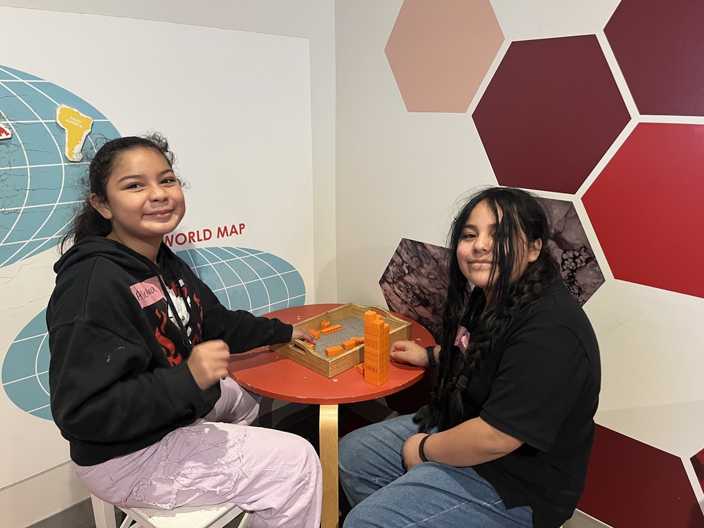 2 students sitting at a round table and using blocks. 