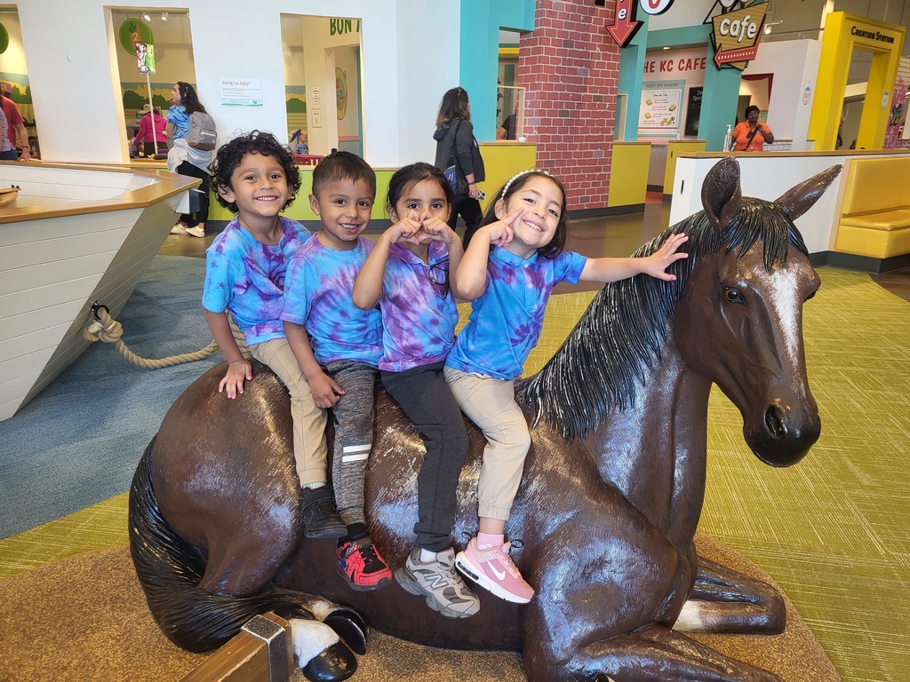 Children happily posing on a plastic horse during their visit.