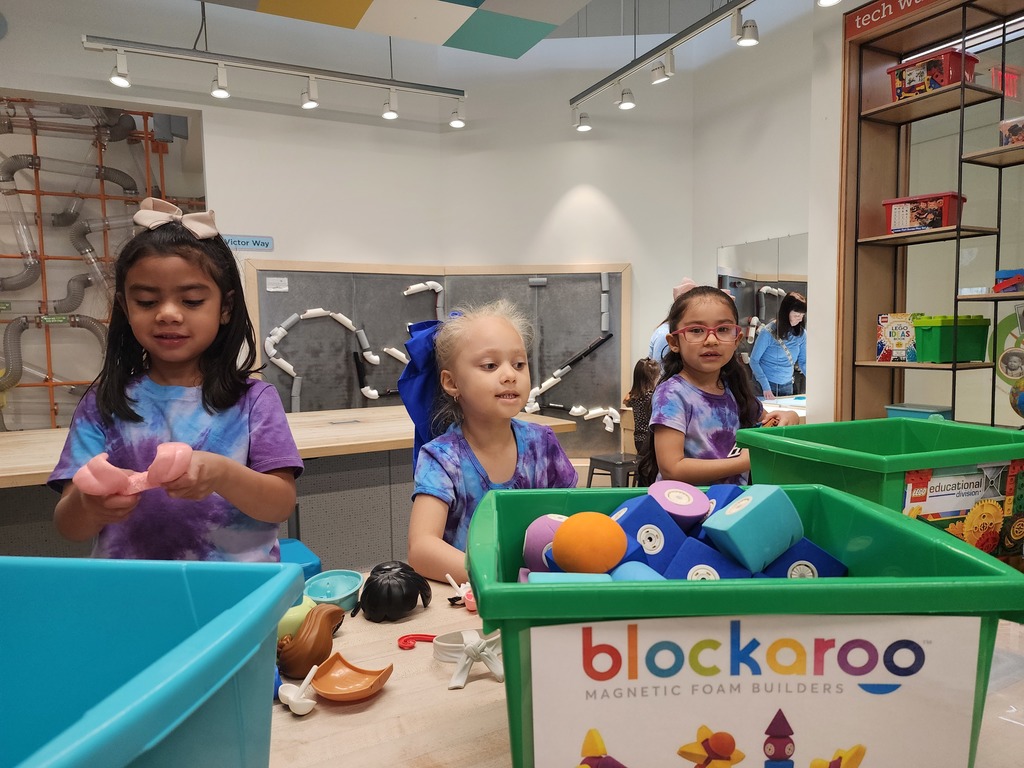 3 girls playing in a children’s museum, putting together puzzles
