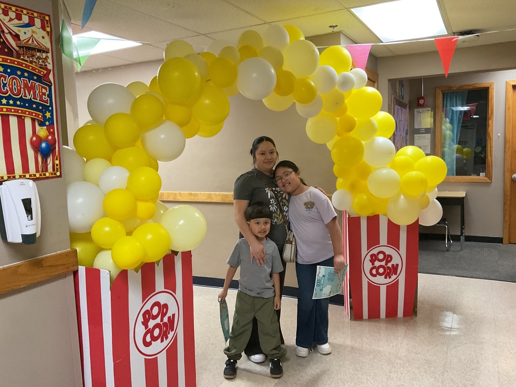 family taking a picture unde the popcorn balloon arch