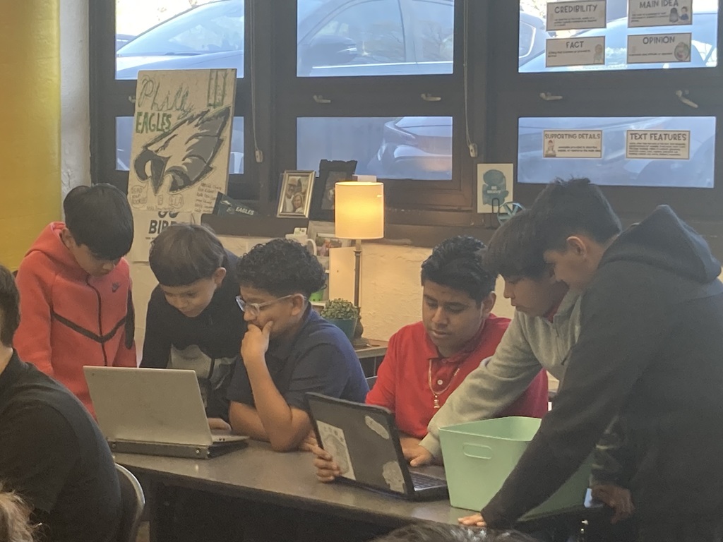 6 students looking at 2 laptops 