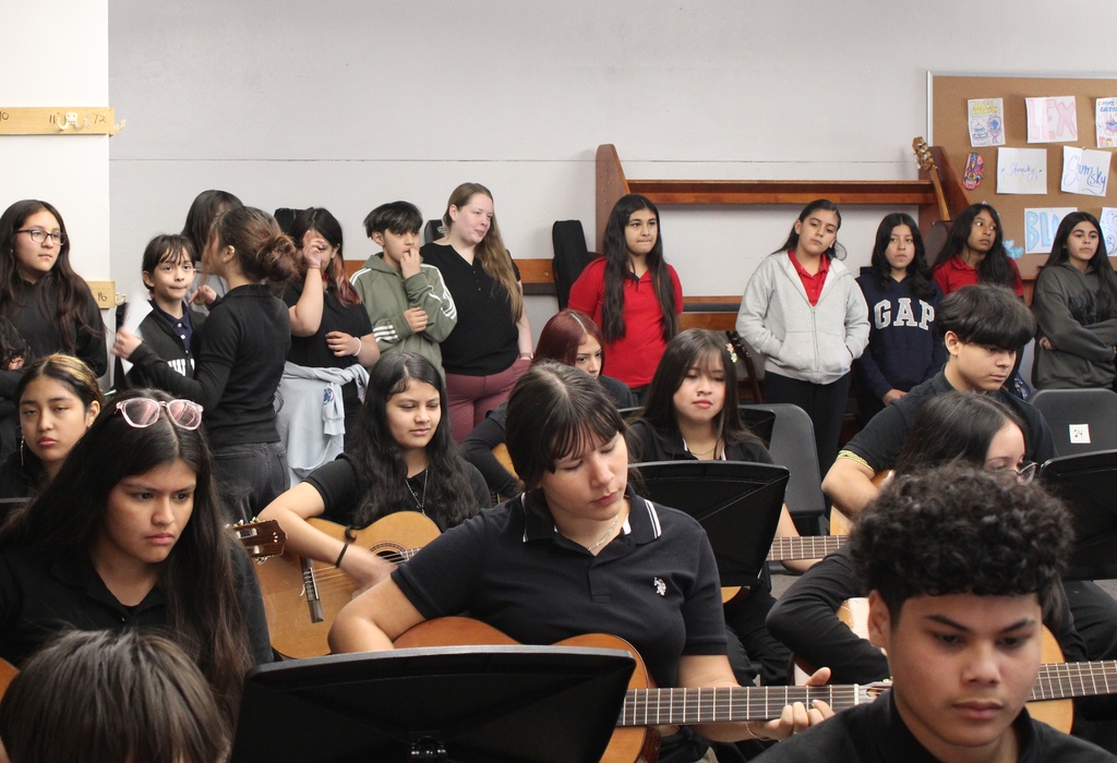 students in the back of the classroom watching other students in music class. 