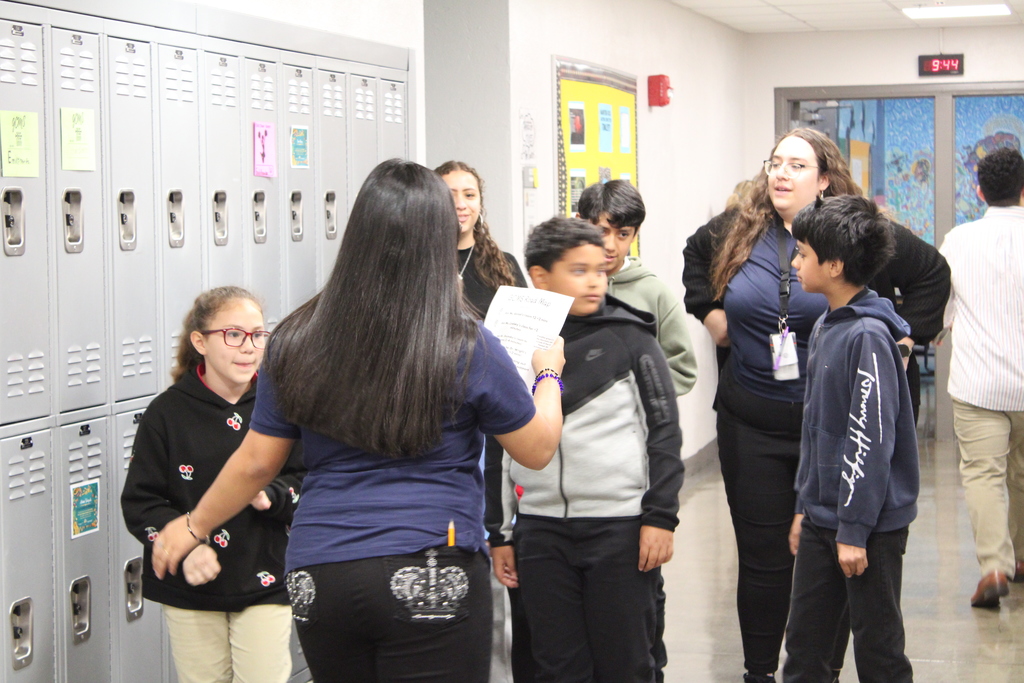6 students and one teacher in the middle of the hallway by the lockers