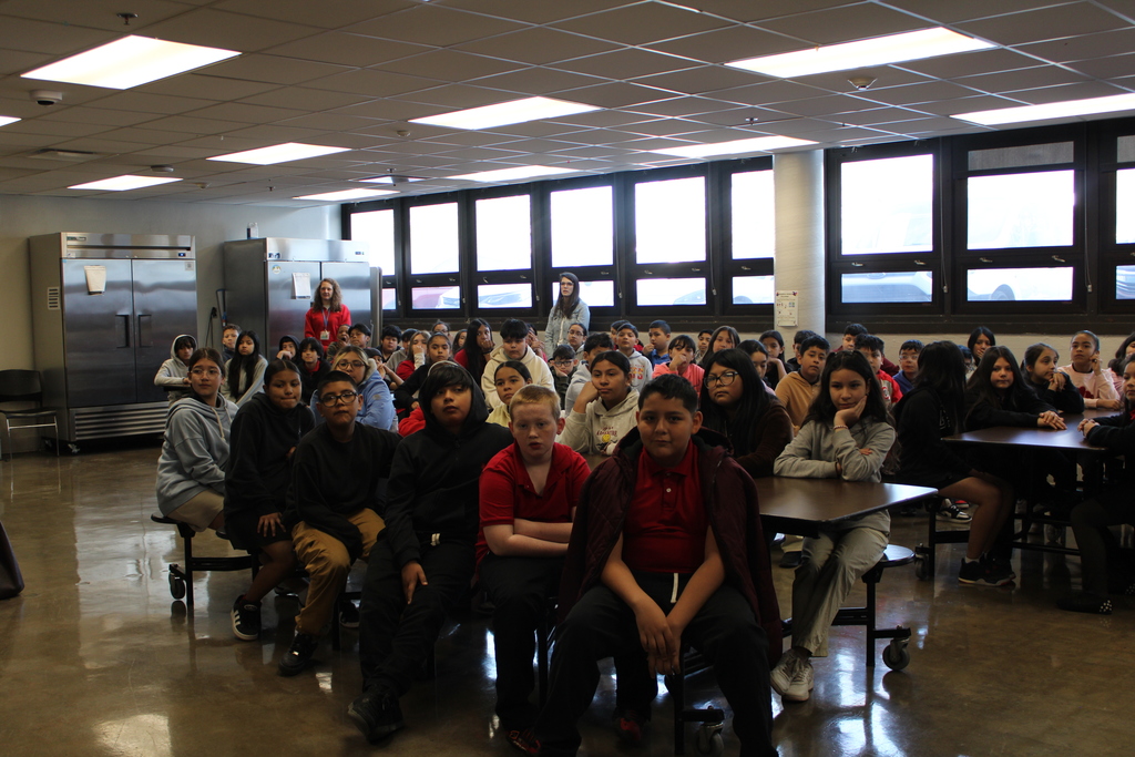 Many students sitting in the cafeteria looking at the camera 
