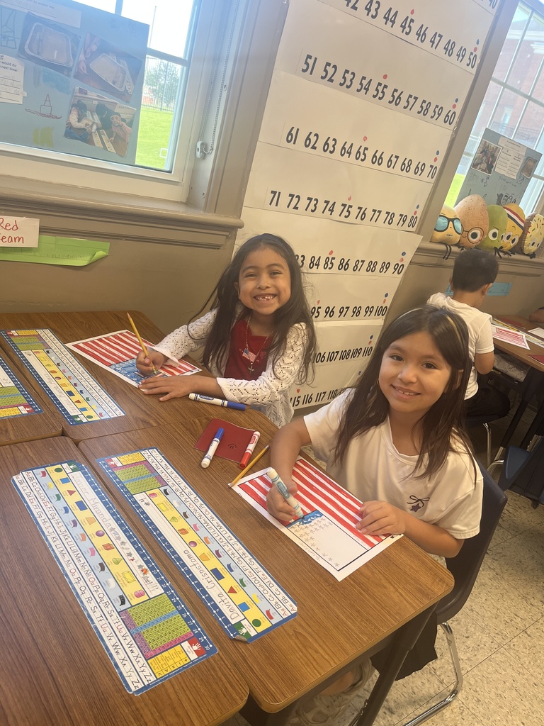 Students siting on chair and desk coloring an American flag 
