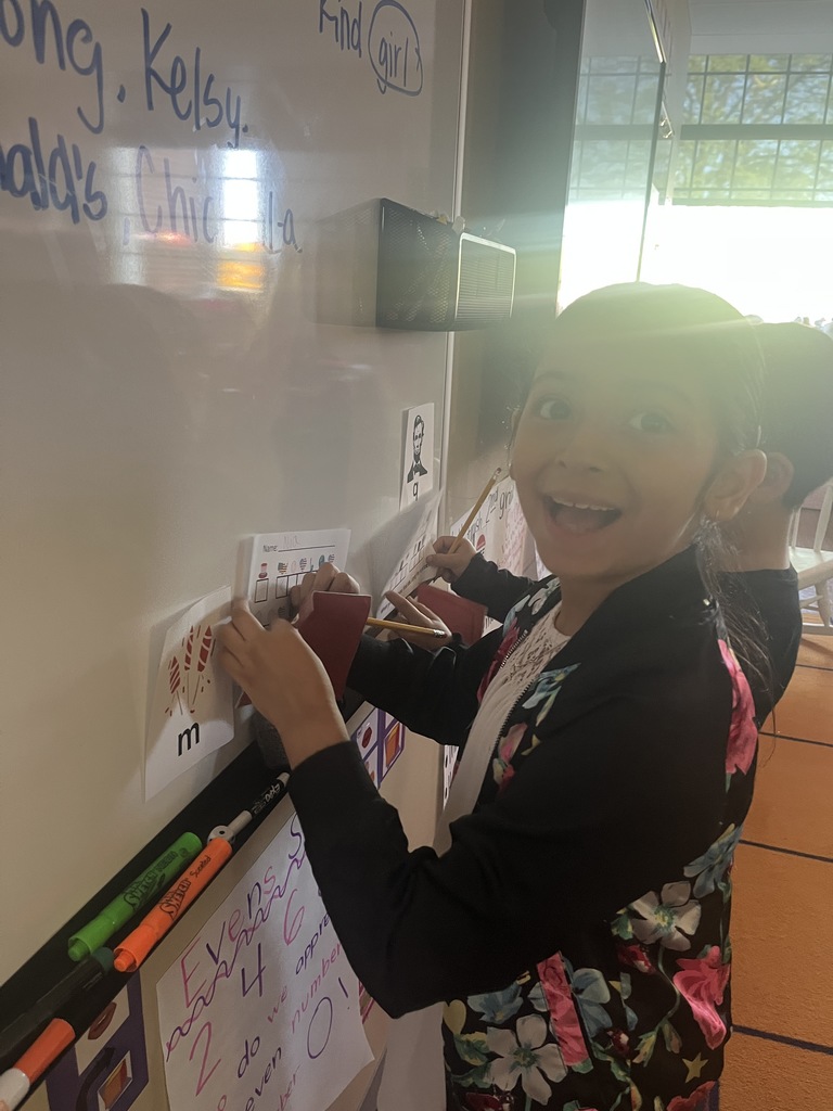 Student smiling while doing a  writing code activity near the board