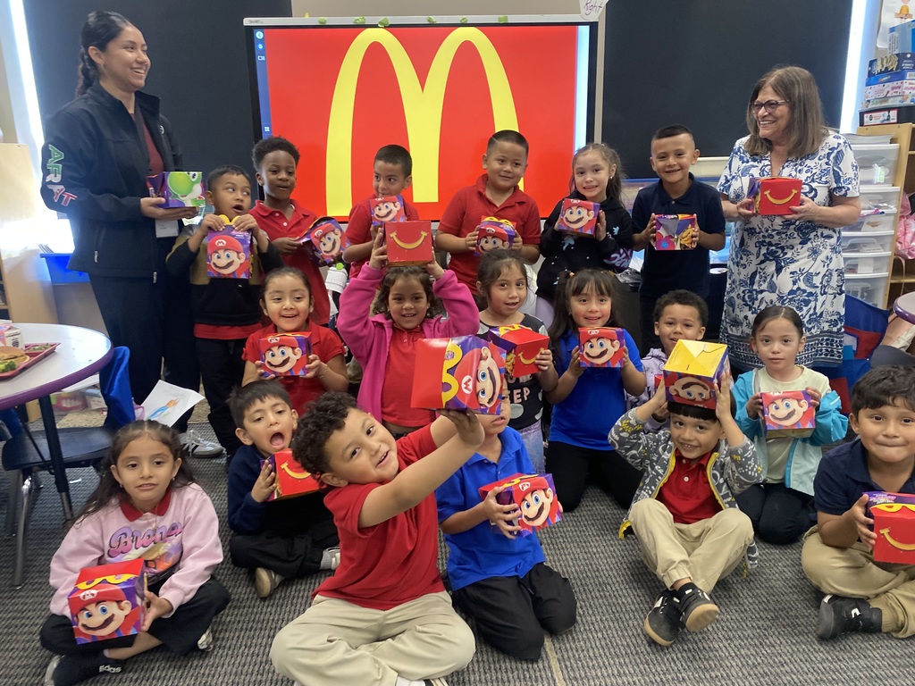 A group of students showing off their happy meals with a Mc Donald's background