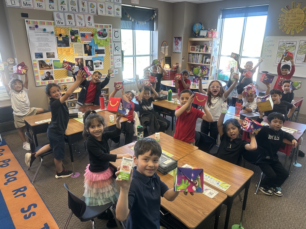 A class holding with hands up holding their happy meal.