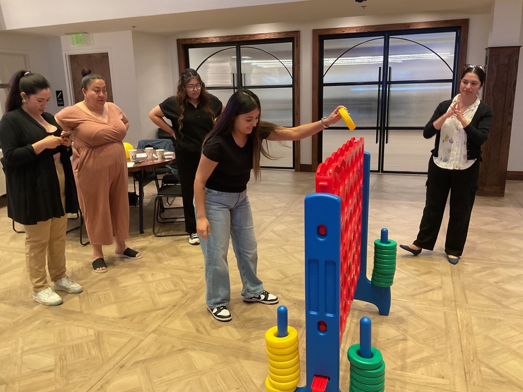 A group of women playing connect four one women putting a yellow chip on the game