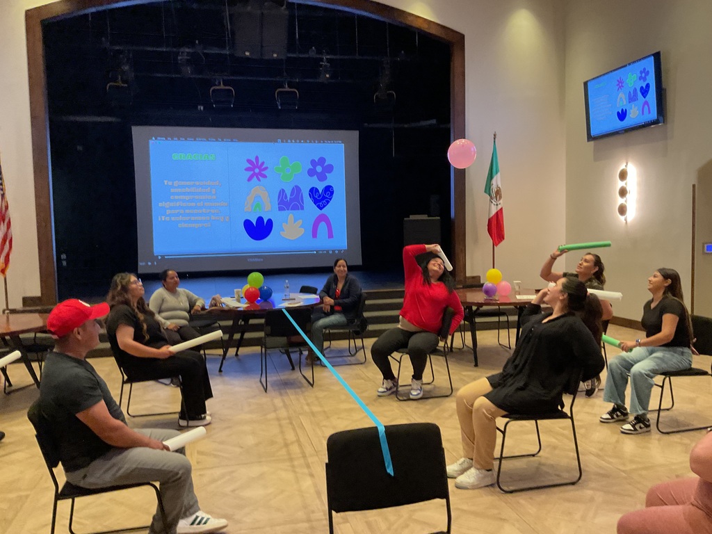 A group of people sitting on chair playing with a balloon