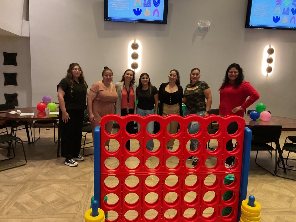 A group of adults posing in front of the connect 4 game