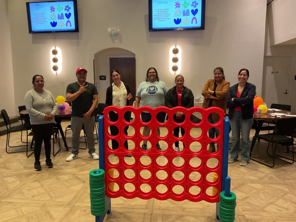 A group of adults posing in front of the connect 4 game