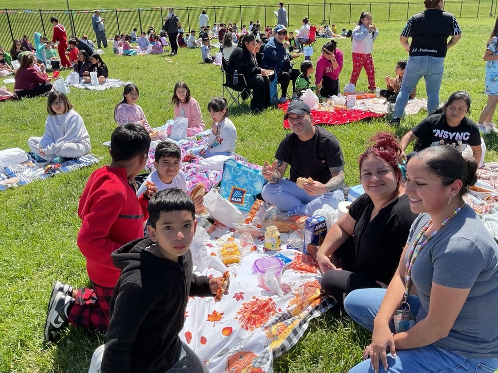 Children sitting together outdoors, enjoying their lunch bags and sharing special moments during a family picnic day.