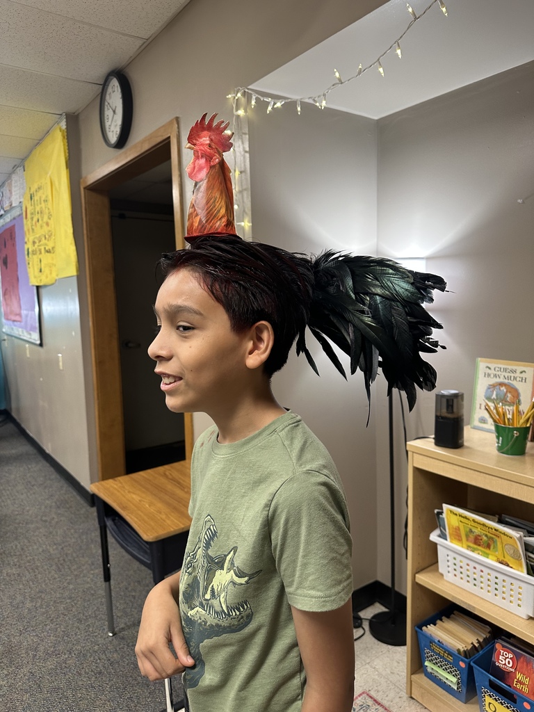 A child showing off a crazy hairstyle with a paper rooster on top of their head.