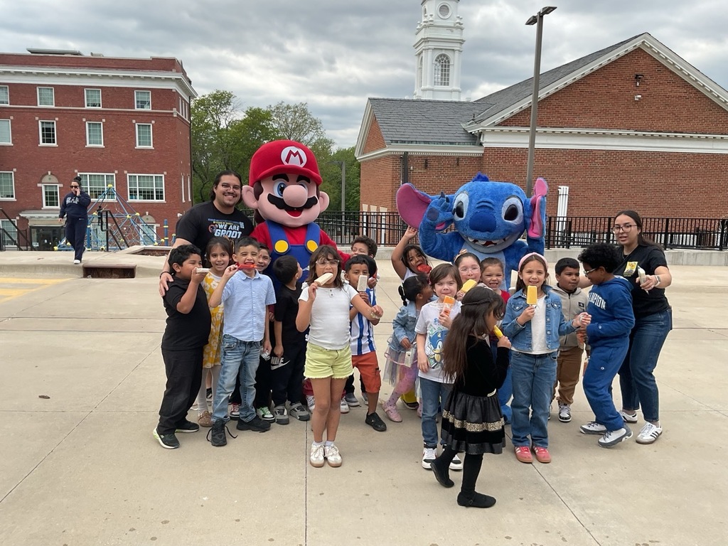A first-grade class posing with Stitch and Mario Bros. characters, along with their teacher and assistant, celebrating Children’s Day.
