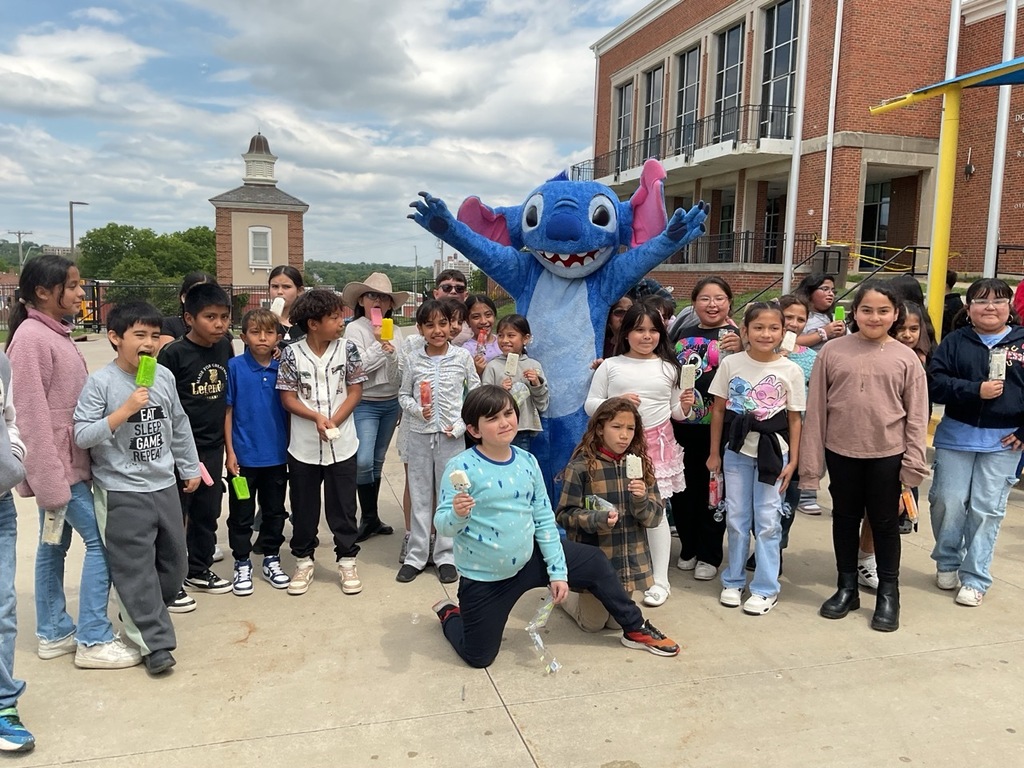 Happy children eating popsicles and posing for a photo with the Stitch character.