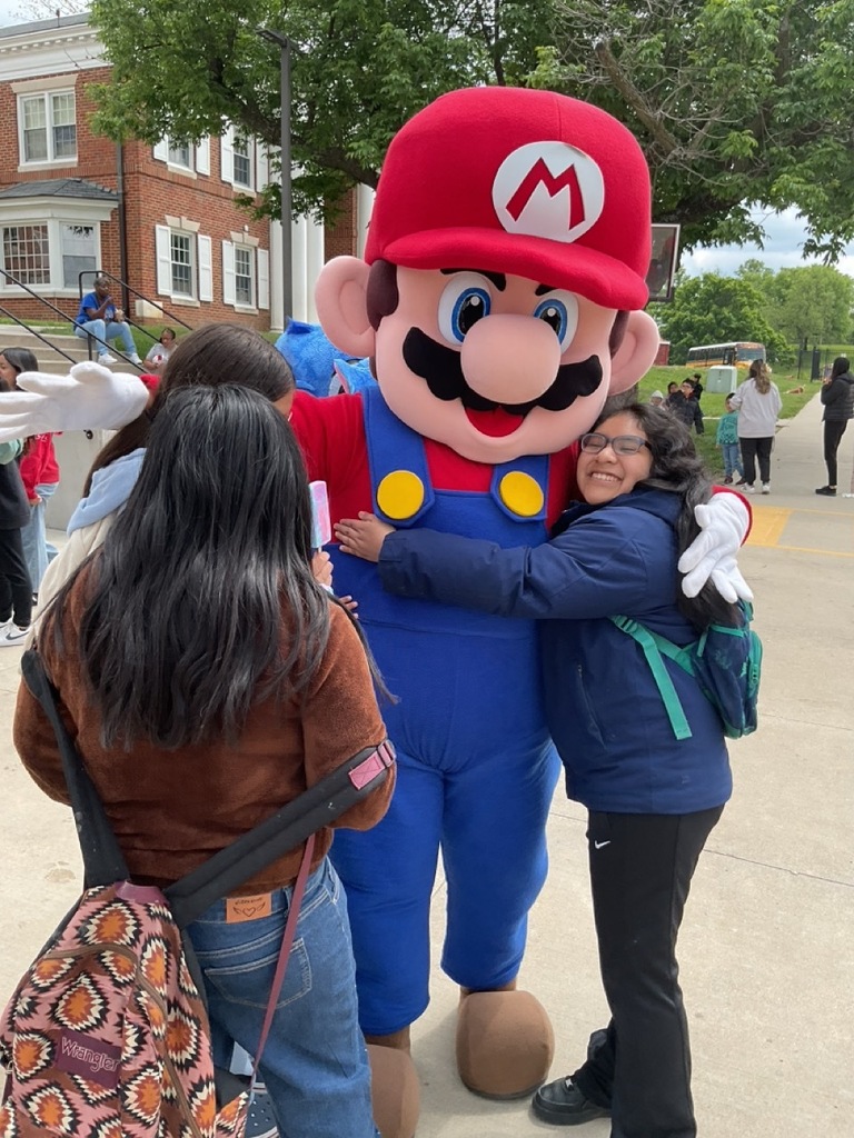 Mario Bros mascot hugging a fifth-grade girl as they celebrate Children’s Day together.