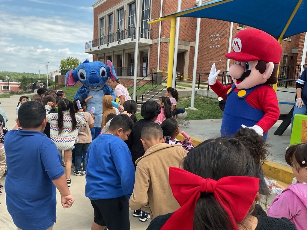 Children lined up, receiving popsicles next to the Stitch and Mario bros mascots.