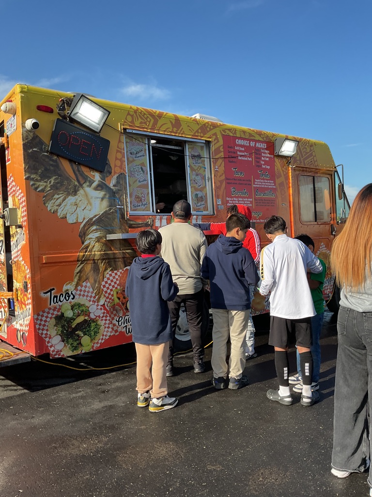 people lining up to buy food from an orange food truck