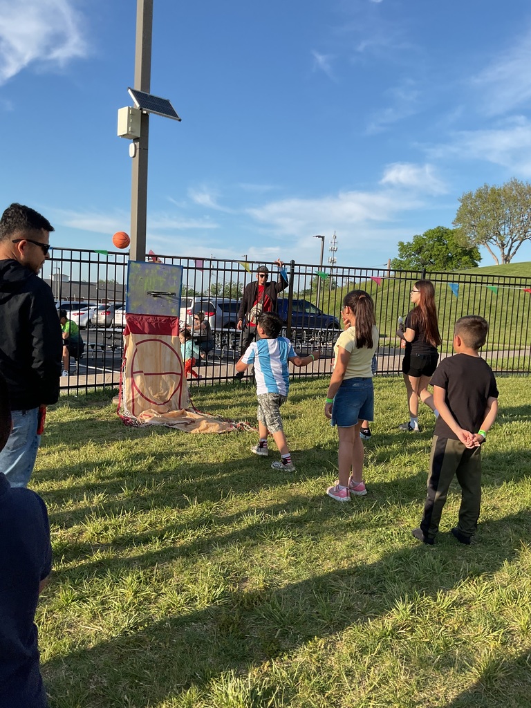 A boy playing a carnival game, of basketball, others watching