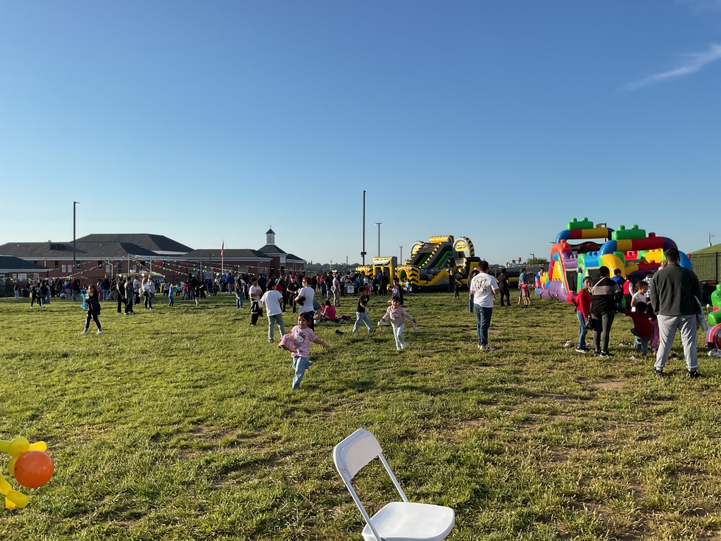 A grass area with people walking and inflatables.