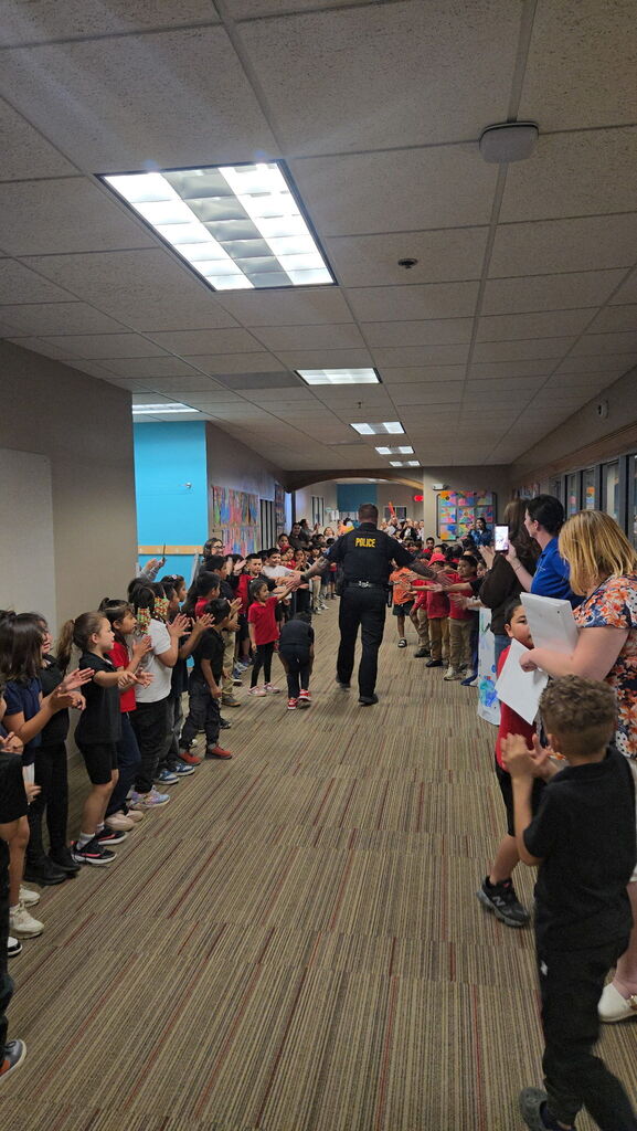 Officer high fiving students in the hall 