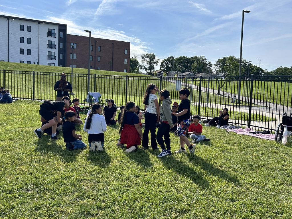 Students sitting, standing and kneeling on the grass