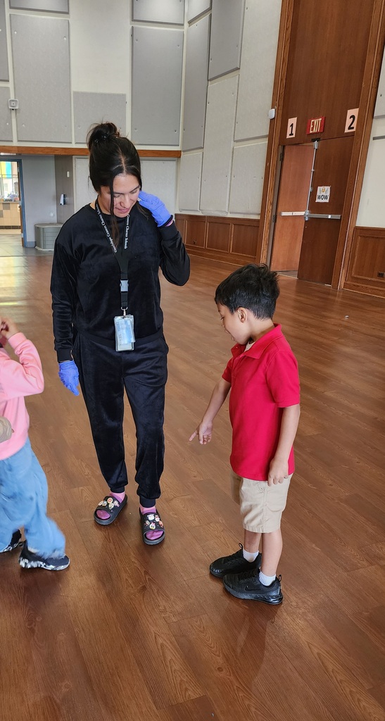 Woman working at a school wearing pajamas, a kindergarten child asking why? This is because there is an Underground Spirit Week for staff.