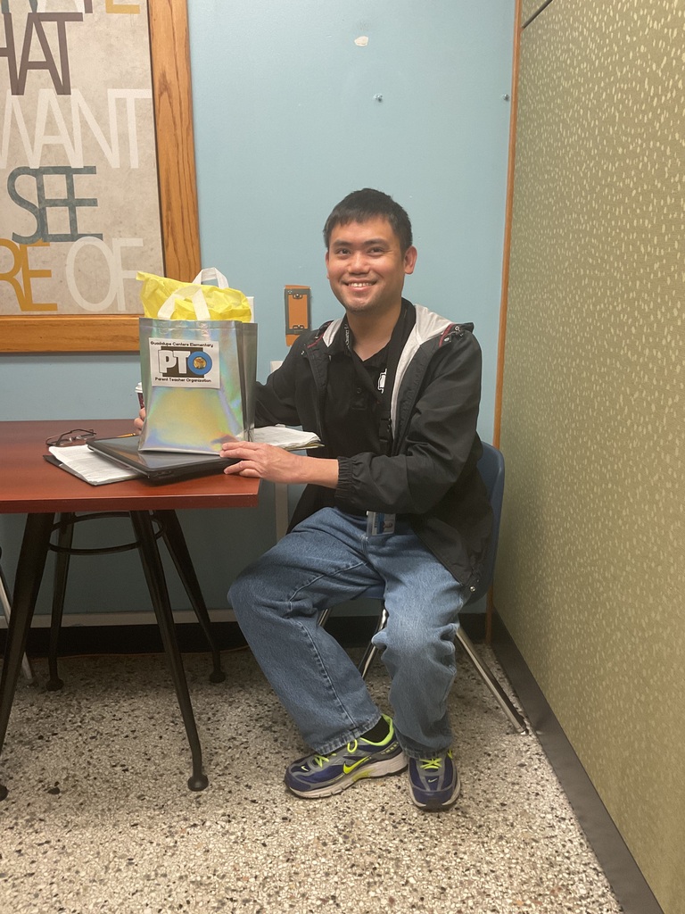 A man sitting on a chair with a gift bag on the table