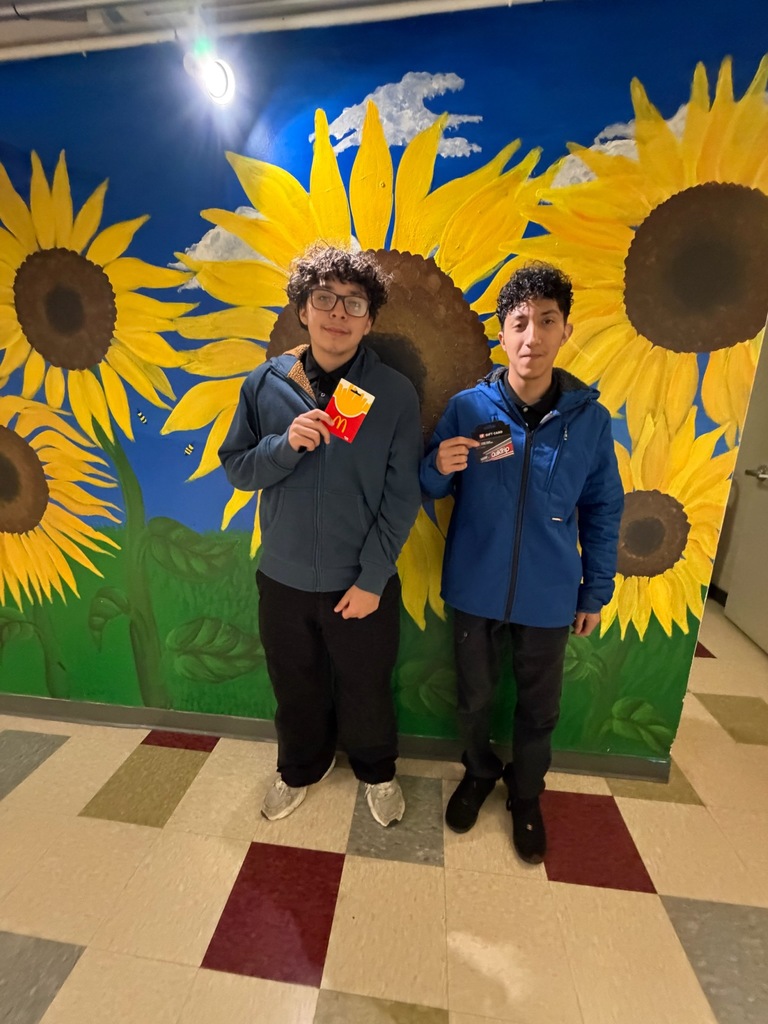 two students in front of a murual