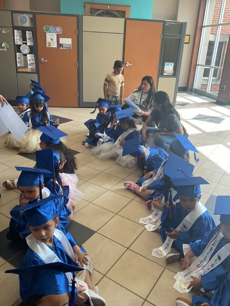 Children sitting in rows, Pre-K graduates wearing blue caps and gowns
