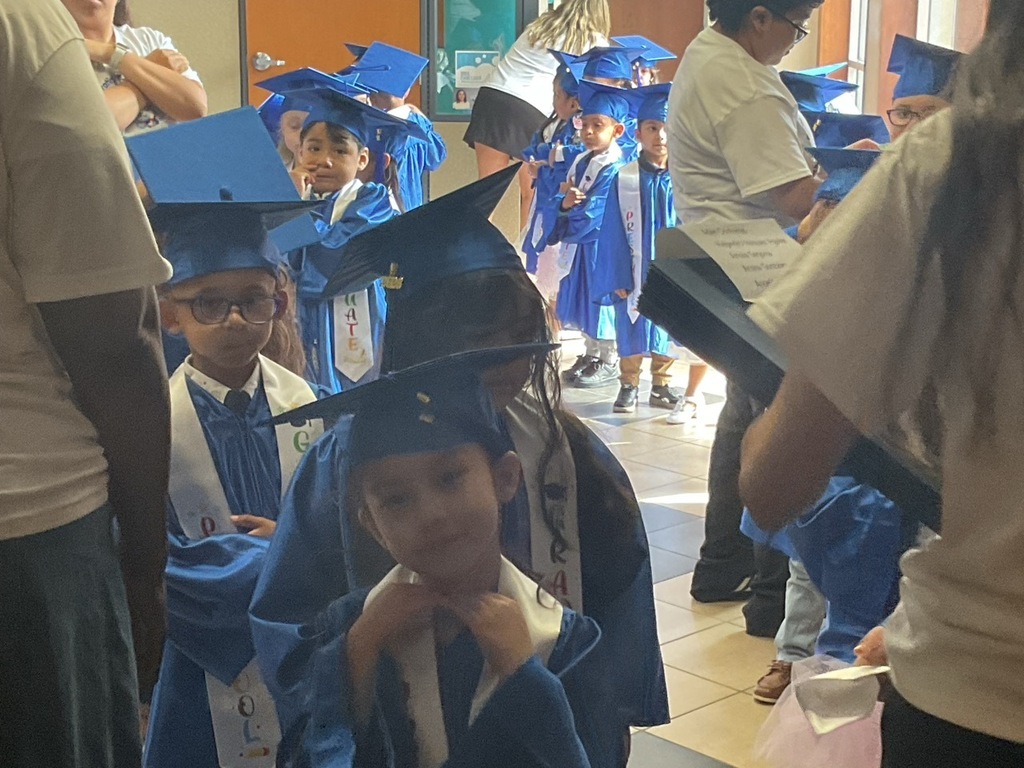 Children lined up and ready for the graduation event, Pre-K students wearing navy blue caps and gowns.