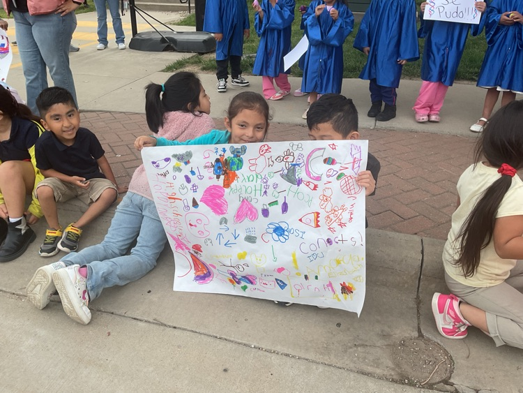 3 sitting students holding signs